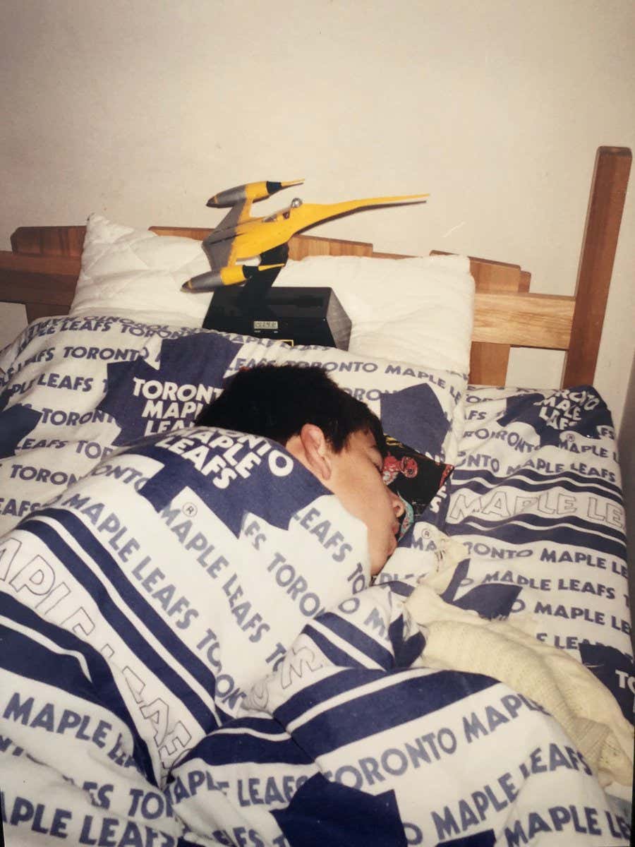 A young John Tavares sleeps under sheets emblazoned with Toronto Maple Leafs wordmarks and logos.