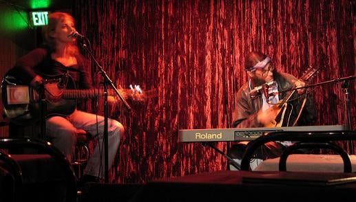 a woman with a guitar and a man with a mandolin on a stage