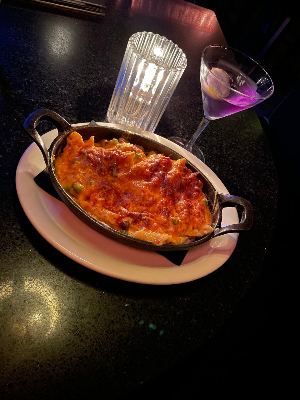 A bowl of mac n' cheese and a martini in candlelight