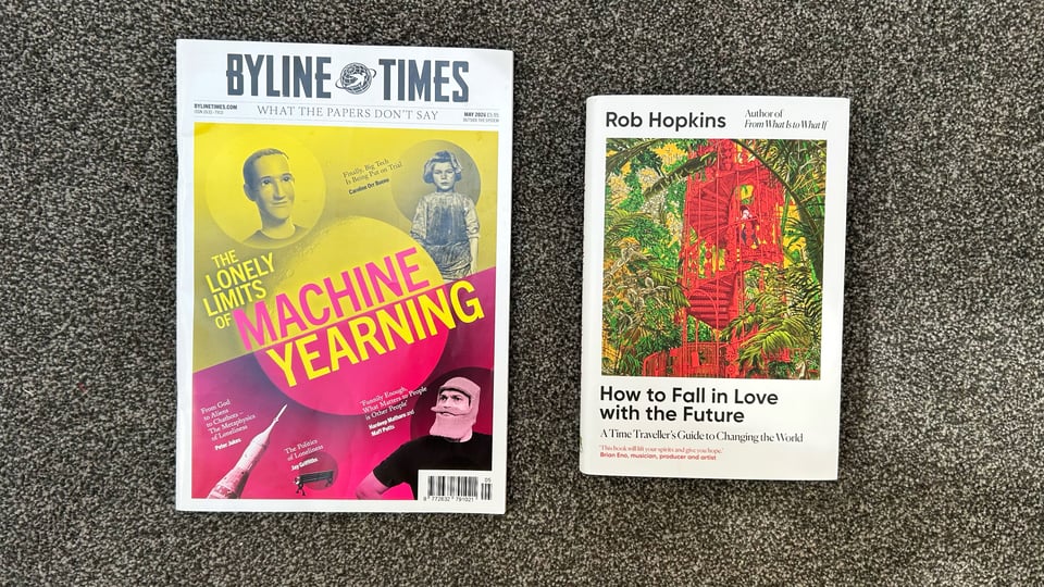 Photograph of a magazine and a book. The magazine is called Byline Times. The headline on the cover is "The Lonely Limits of Machine Yearning." The book is "How to Fall in Love with the Future" by Rob Hopkins. The subtitle is, "A Time Traveller's Guide to Changing the World."