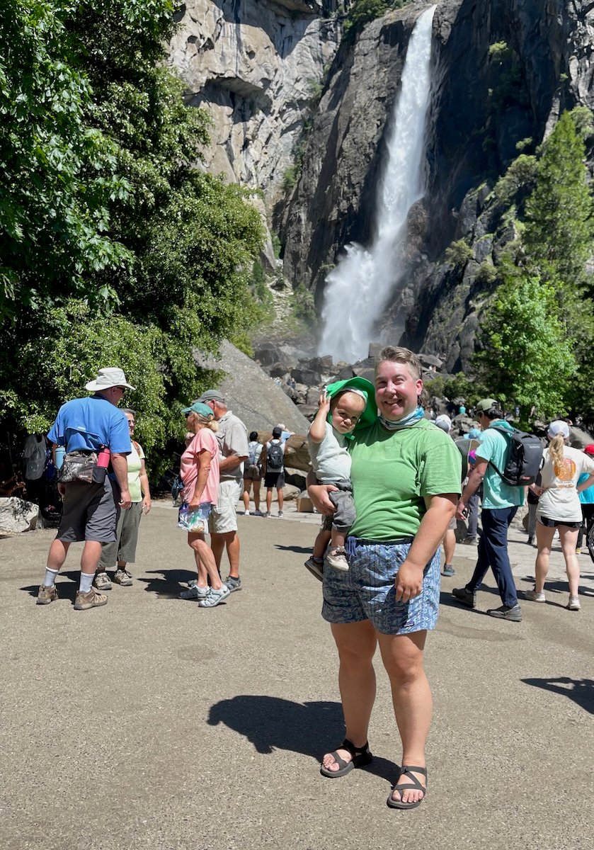 the author holds their son in front of a waterfall