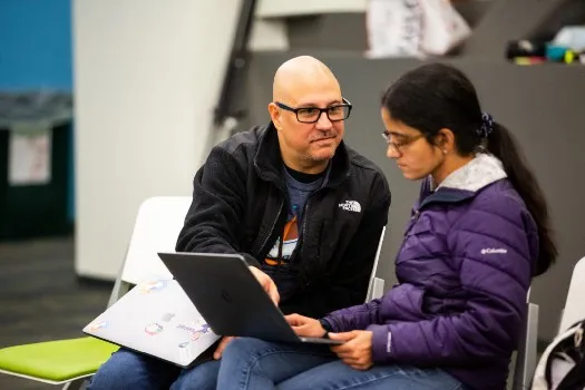 VMware accessibility engineer Chris Lane at Accessibility Hackathon showing VMware developer Gaayathri Meenakshi Sundaram how to code in ARIA. Photo by Jeffrey Kuo.