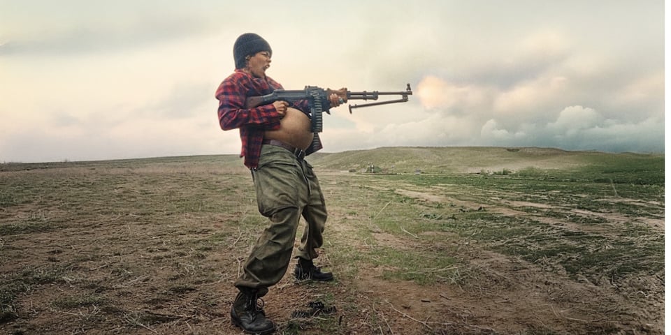 A pregnant woman shooting a machine gun and screaming.