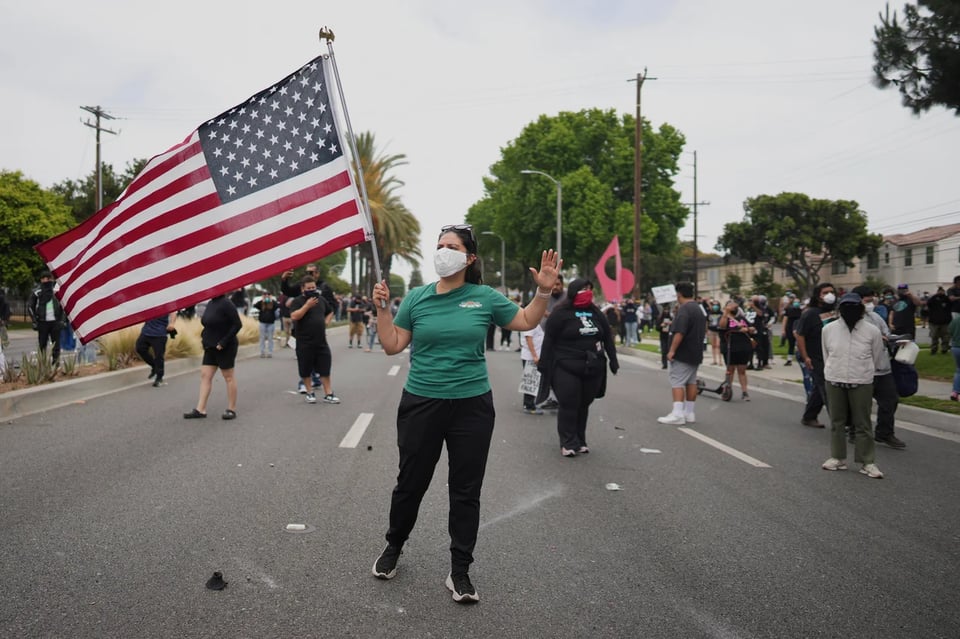 protestor waves USA flag in Paramount California on June 7