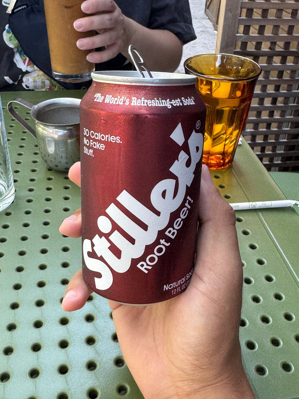 My hand holding a can of Stiller's Root Beer, which was disgusting, falsely claiming to be "The World's Refreshing-Est Soda"