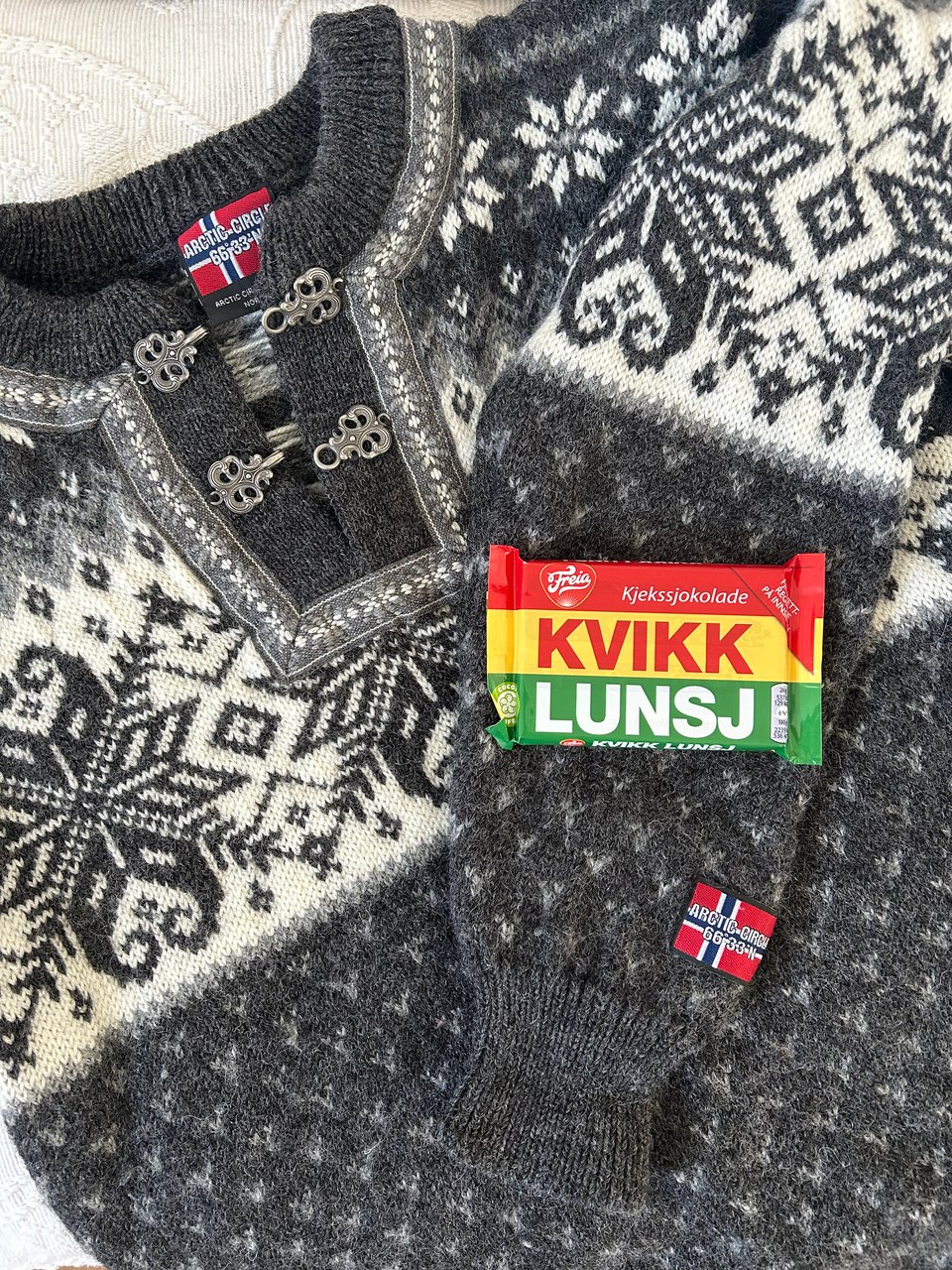 A bar of Norwegian chocolate called Kvikklunsj is on a grey and cream handknitted Norwegian jumper with some large geometric patterns. Image by Rowan Ambrose.