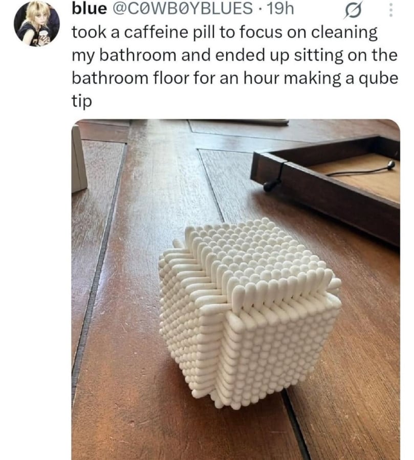 Tweet from @C0WB0YBLUES: "took a caffeine pill to focus on cleaning my bathroom and ended up sitting on the bathroom floor for an hour making a qube tip". Beneath is a photo of hundreds of Q-tips arranged and interlocked into a cube shape.