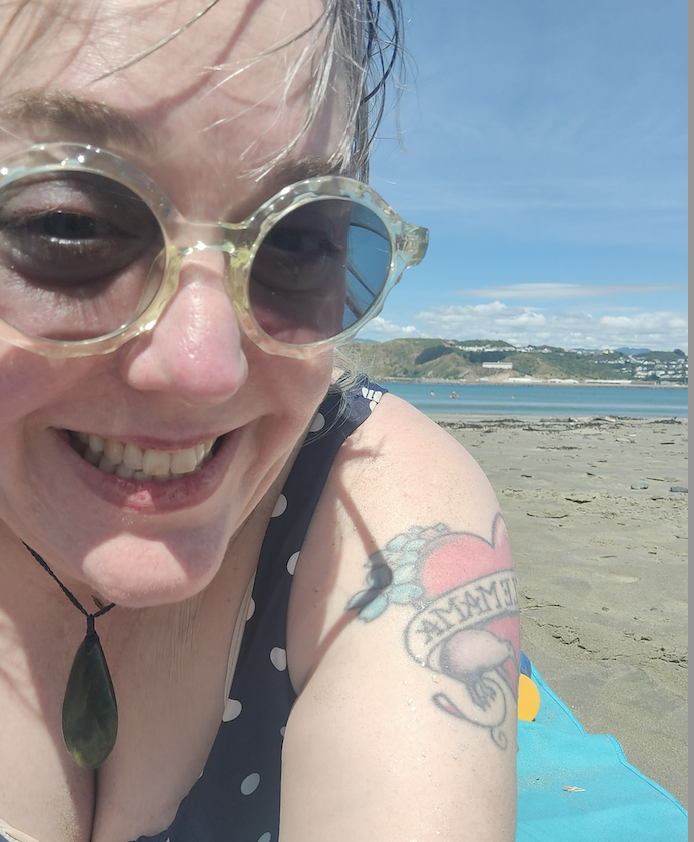 rachael, a white woman with wet gray hair, on blue towel at beach in the sun