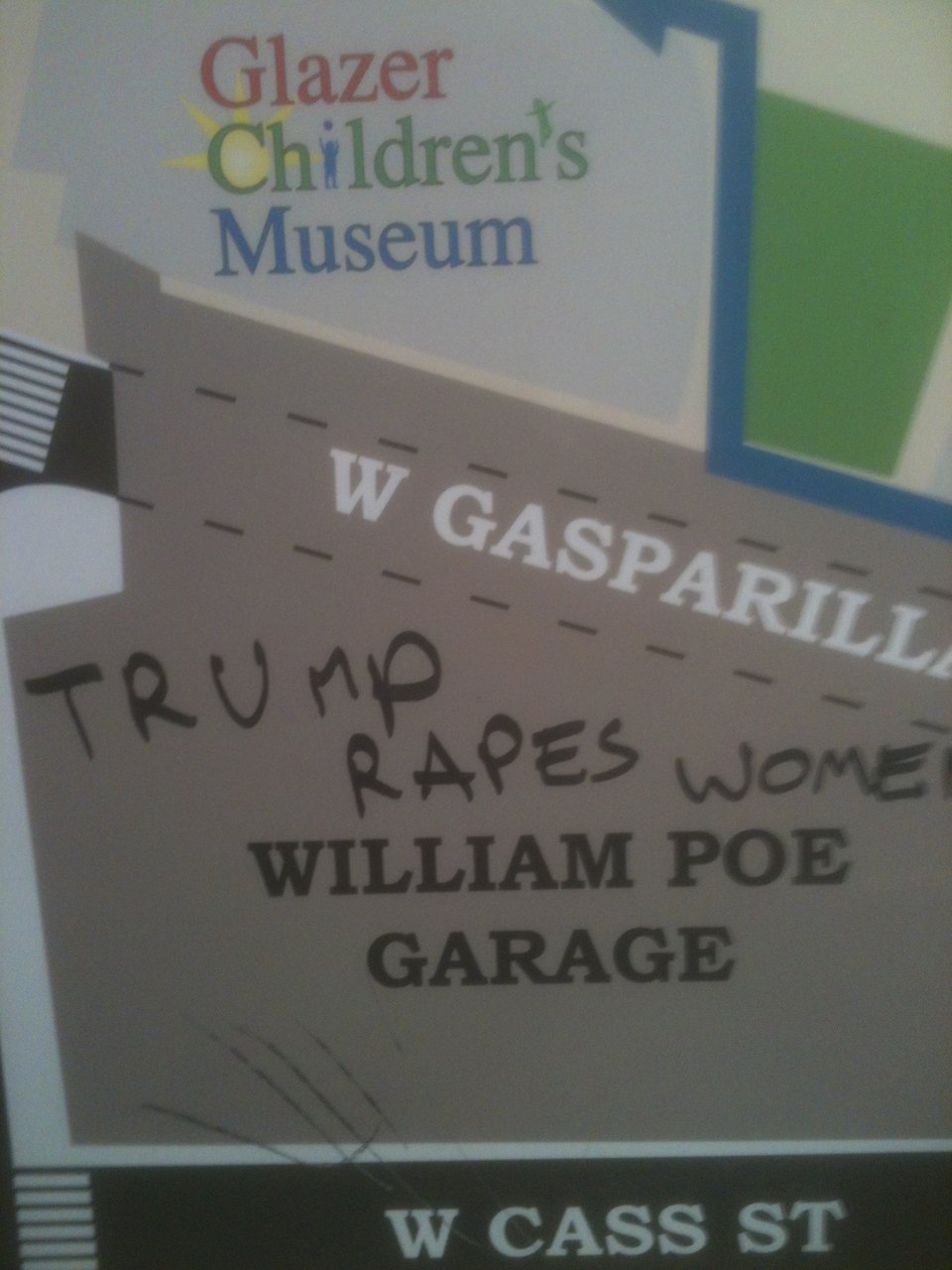 a map inside a parking garage, graffitied with the words "Trump rapes women."