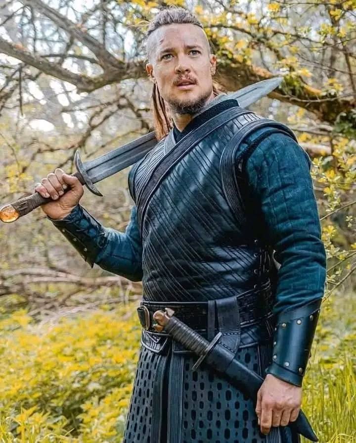 a handsome, dark-haired man stands around holding a sword while looking pretty and somewhat befuddled in period costume