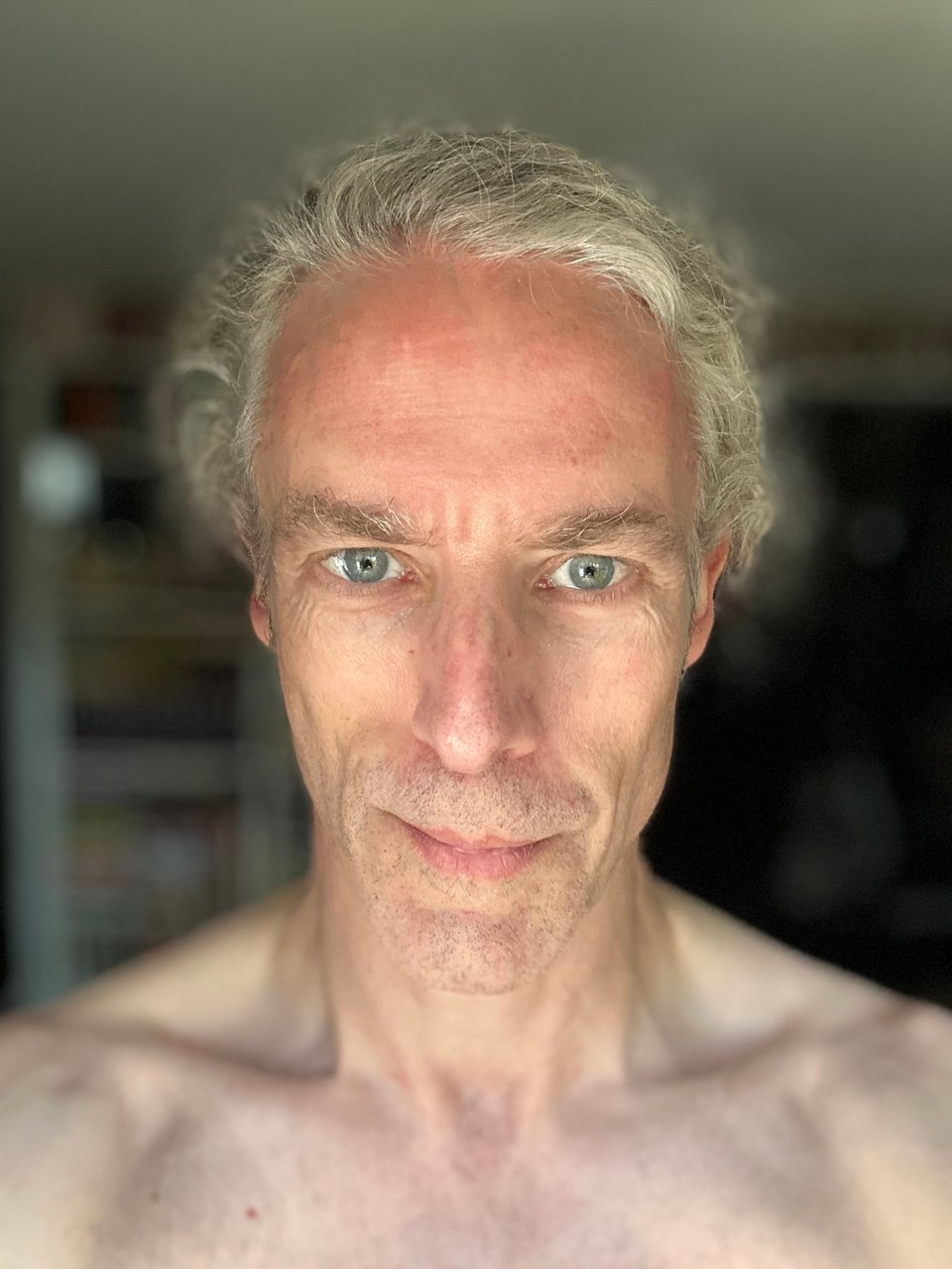 Selfie of shirtless white man smirking at the camera. He’s got no facial hair, and that reveals some thin lips.