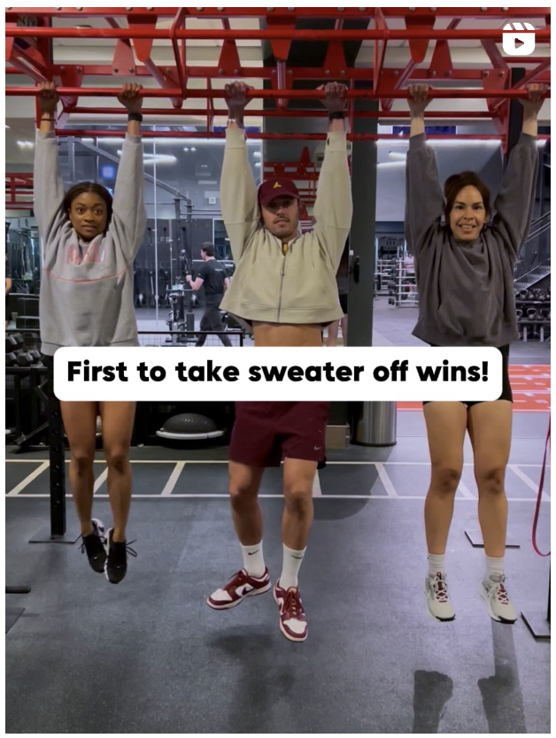 Video still showing three people hanging off of a bar. The text over the still says "First to take sweater off wins!".