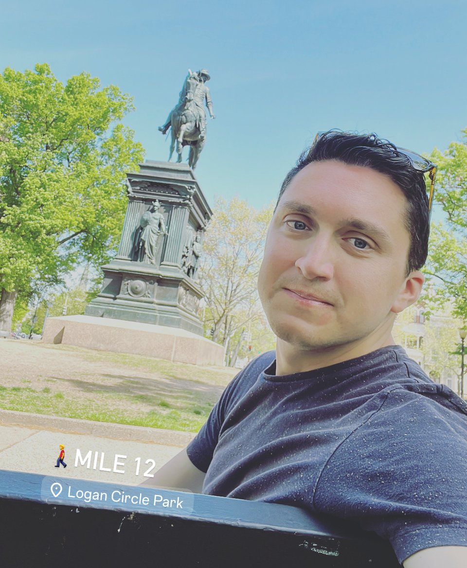 a man taking a selfie in front of a statue