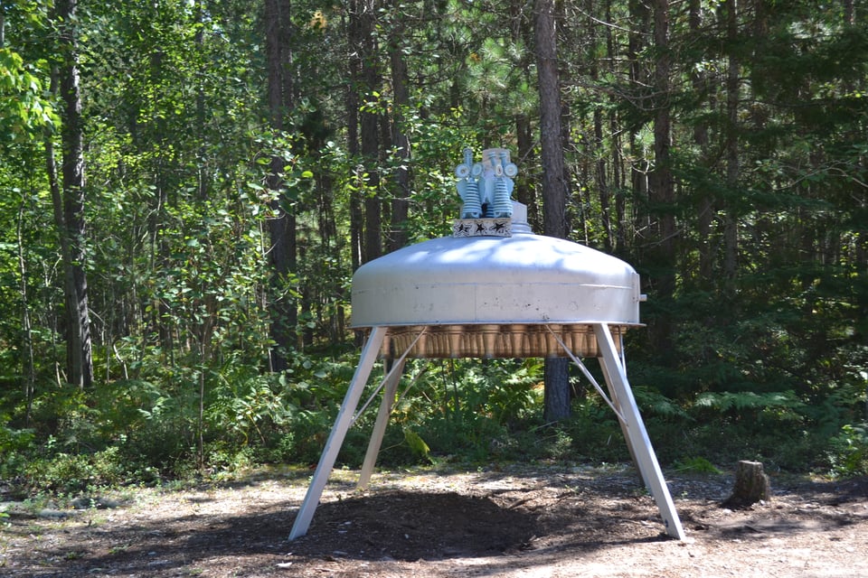 A sculpture of a spaceship on landing struts, with two little blue men on top.