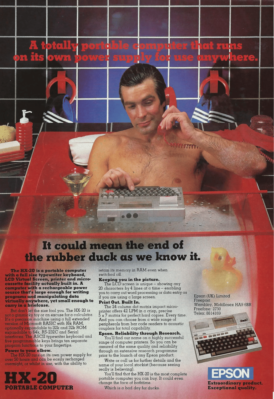 A man sitting in a soapy red bathtub, holding a telephone to his ear, and typing on a small computer sitting atop a glass platform above the tub. There is also a yellow rubber duck near his feet.