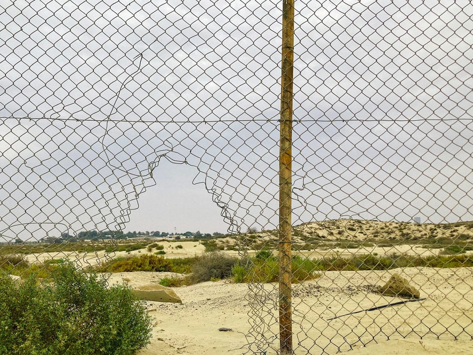 A wire fence with a large hole in it. Photo by Vanburn Gonsalves on Unsplash.