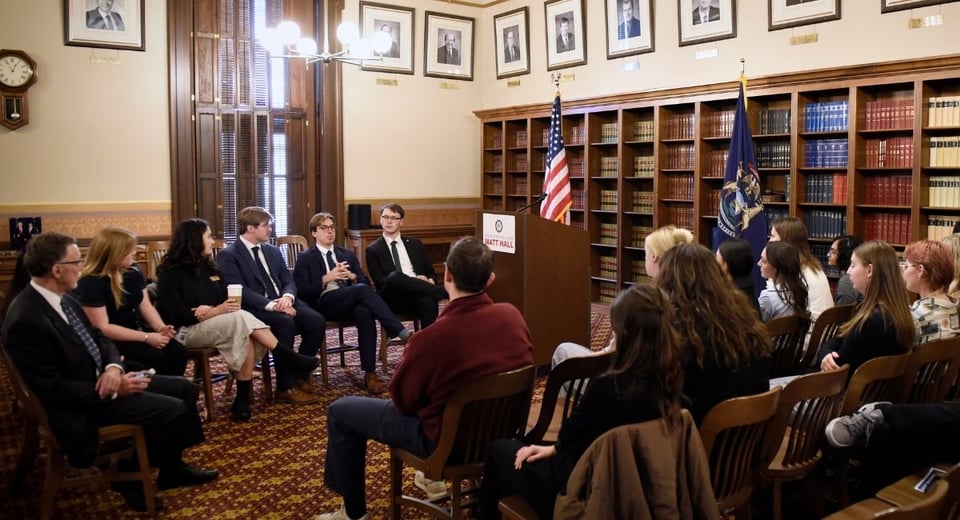 Photo shows a group of Madison alumni and students meeting inside the Michigan Capitol building.