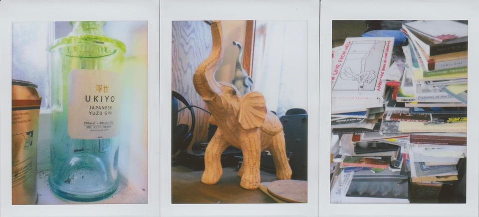 scan of 3 Instax photos: left, a green-blue bottle of Japanese yuzu gin; center a small sculpture of an elephant, with another one behind it; right, two haphazard piles of postcard-books