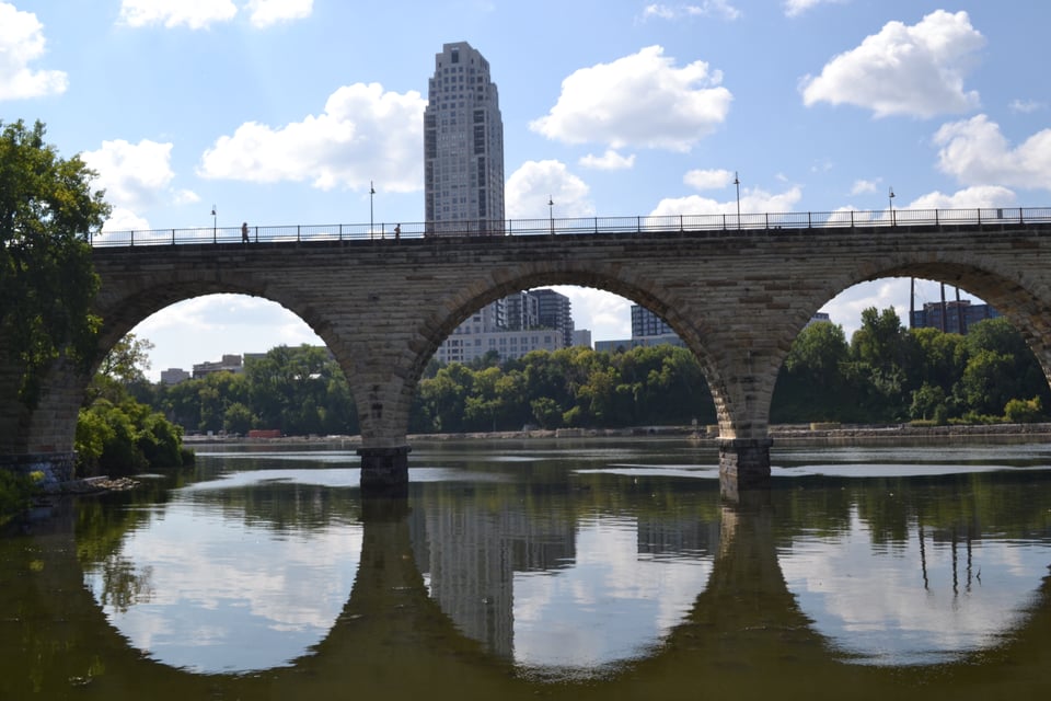 A stone bridge with arches, the reflection in the water turning them into complete ovals.