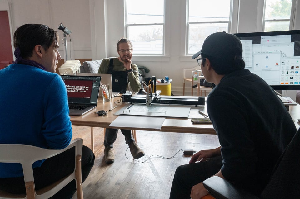 A different group of people around a different table looking at a pen plotter.