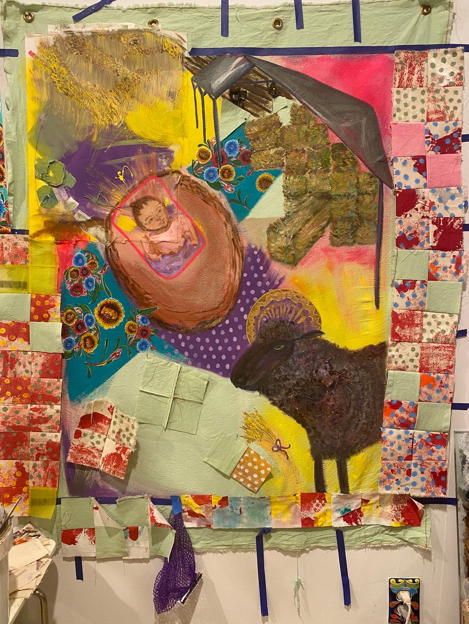 A sheep and a baby in a pole barn manger scene with pieced blocks around the edge of the painted scene