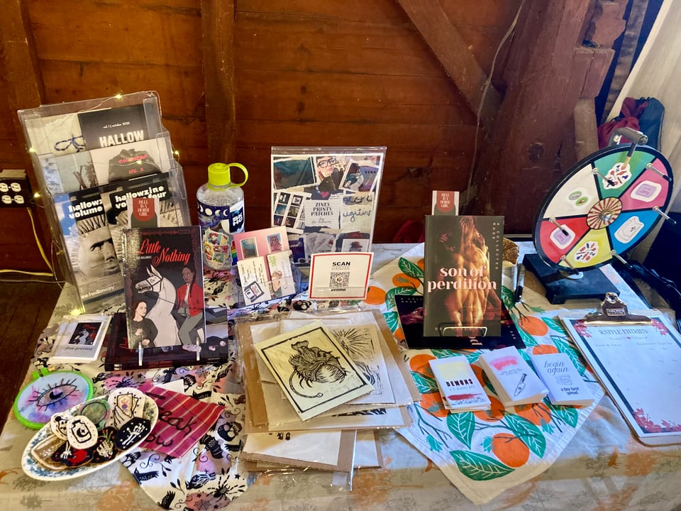 my table, complete with books, zines, embroidered patches, selections of linocut prints, and a prize wheel.