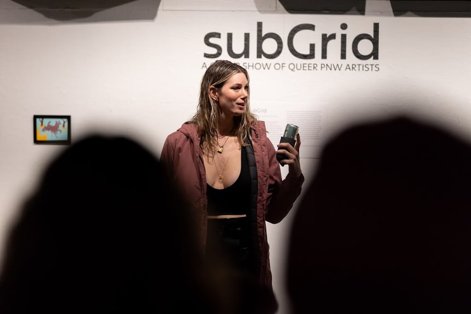 Me presenting at subgrid wearing shiny black pants and a long coat
