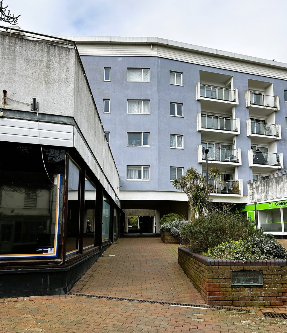 Looking along Pellew Arcade. It runs under the block of flats, then becomes  the underpass leading to the library. There are some brick planters and the only occupant appears to be an accountants.