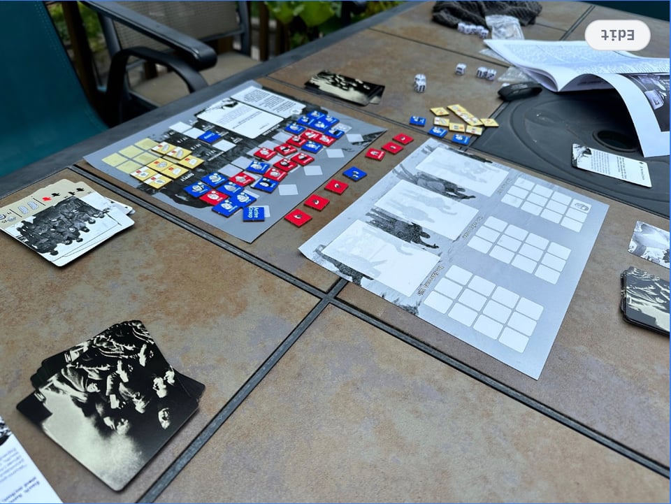 A picture of the game Endurance, with red and blue tiles laid on and around two mats with black and white photographs printed on them.