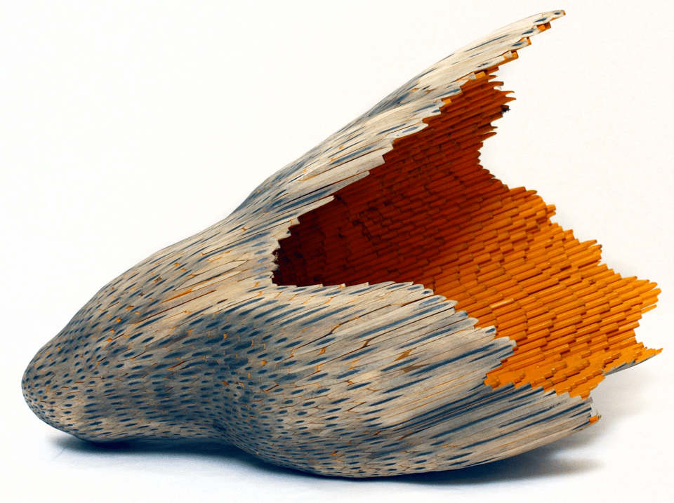At first glance it looks like a seashell, or the organic husk of something convex and U-shaped. Then you  see that the inside is orange and appears to be made of hundreds of pencils fused together