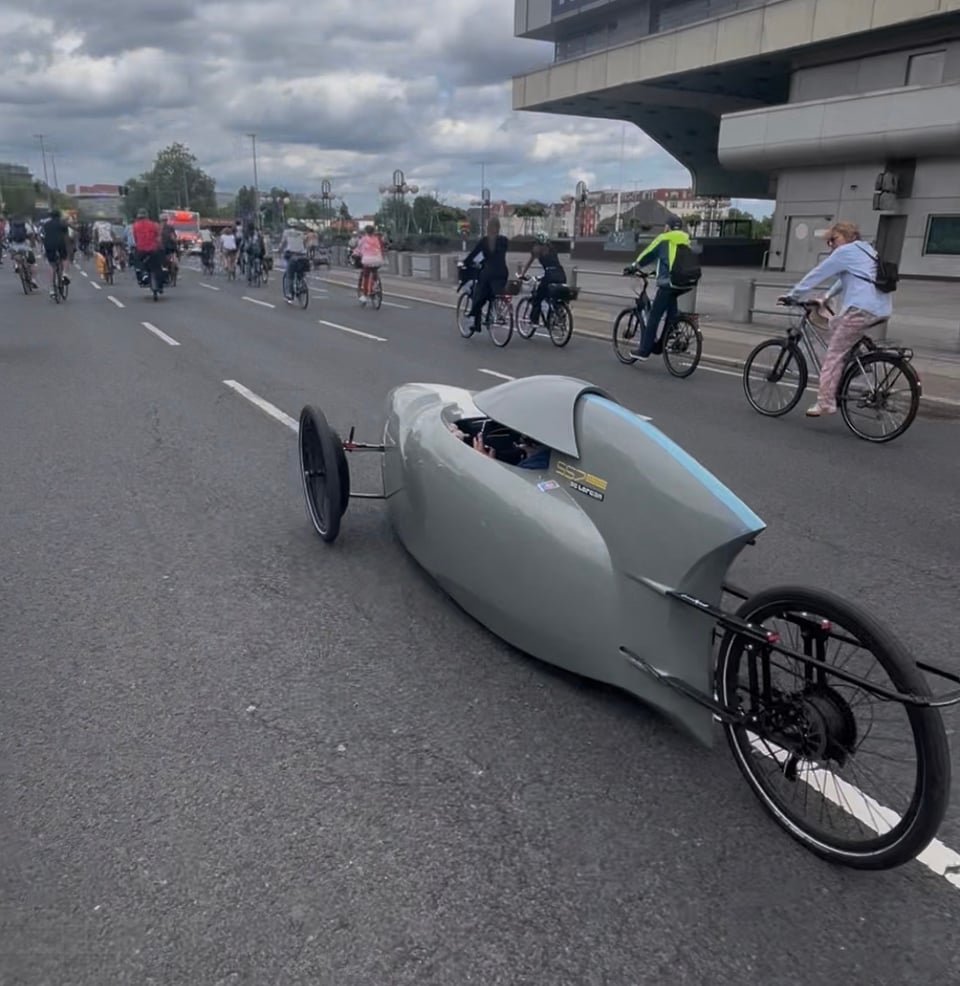A futuristic spacecraft-shaped bicycle with three wheels very low to the ground.