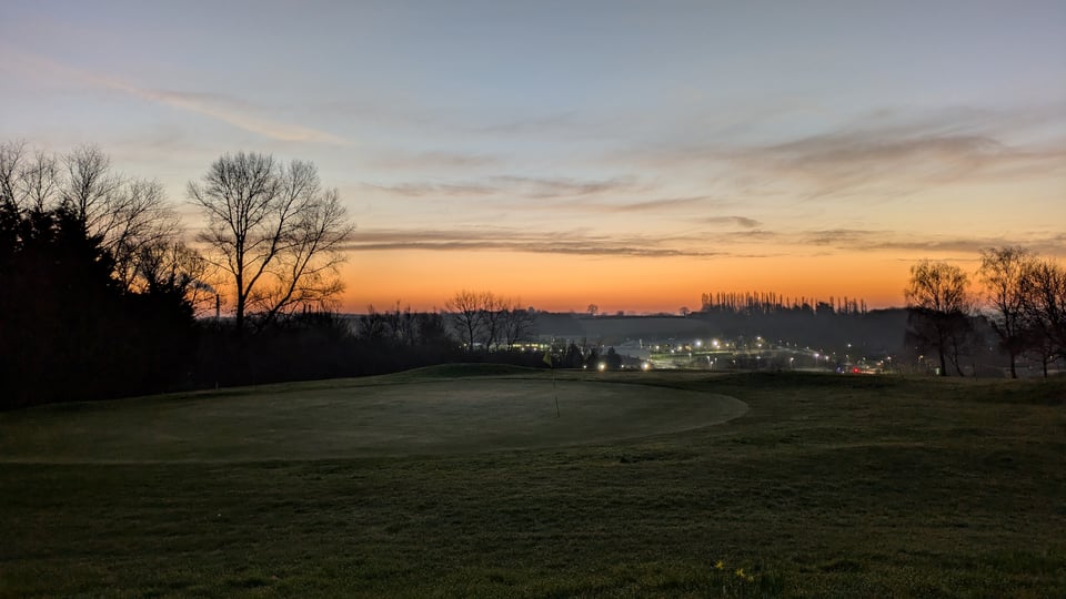 Dawn view from the back of the 18th green at Rushcliffe, lights twinkling from Gypsum Works in the background