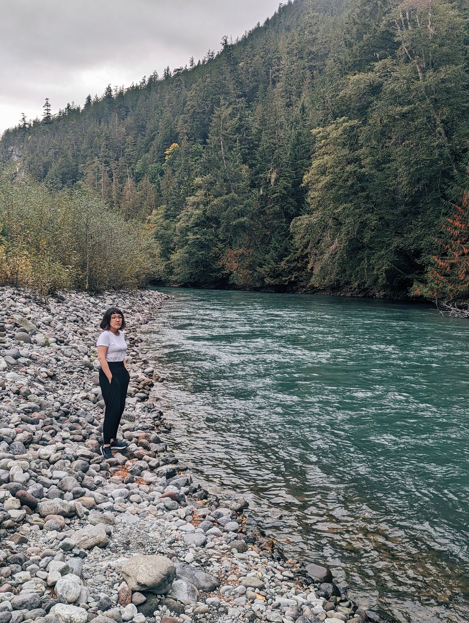 a woman standing on the shore of a river
