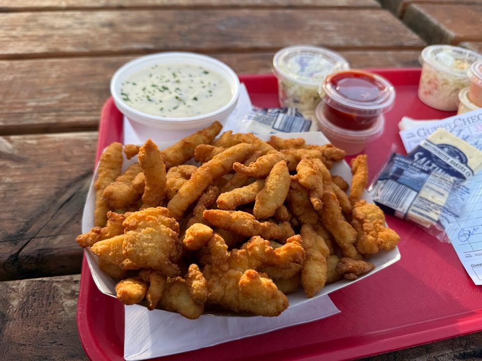 A tray of fried clam strips, clam chowder, and various sauces.