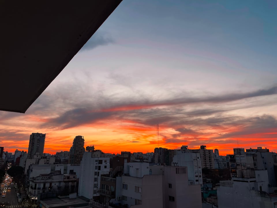 The sun already set, but the horizon is still lit with orange and purple hues. The dark skyline of buildings stretches to the horizon.