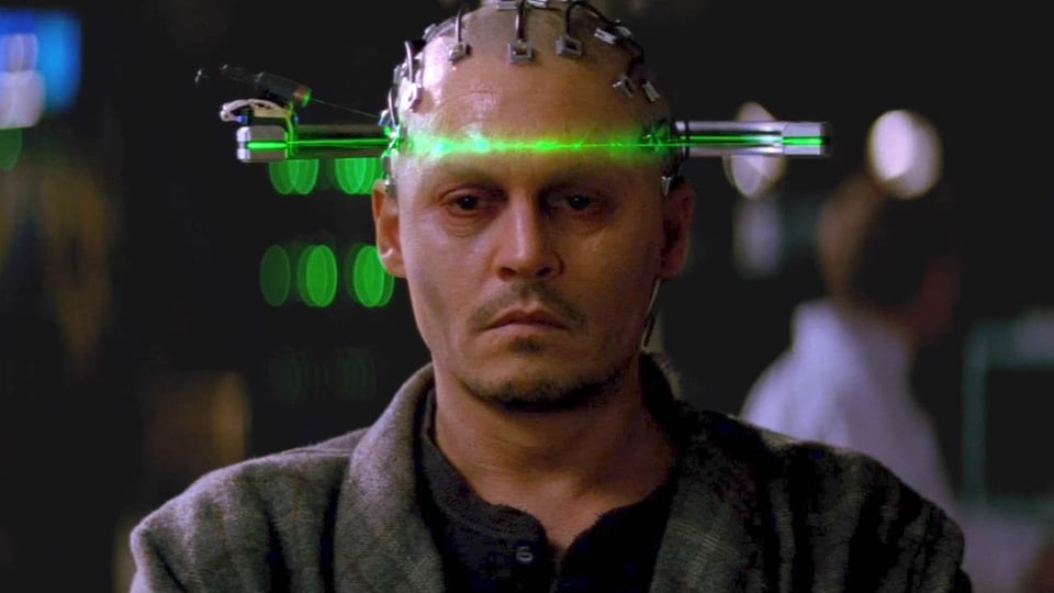 An image of Johnny Depp as Will Caster, with wires directly plugged into his bald head and a green laser scanning his face