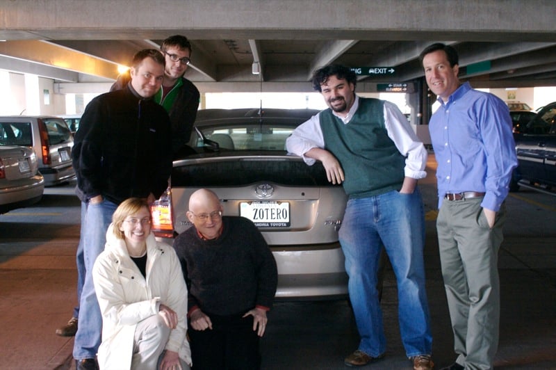 Six people stand and kneel around a Toyota Prius with the license plate "ZOTERO"