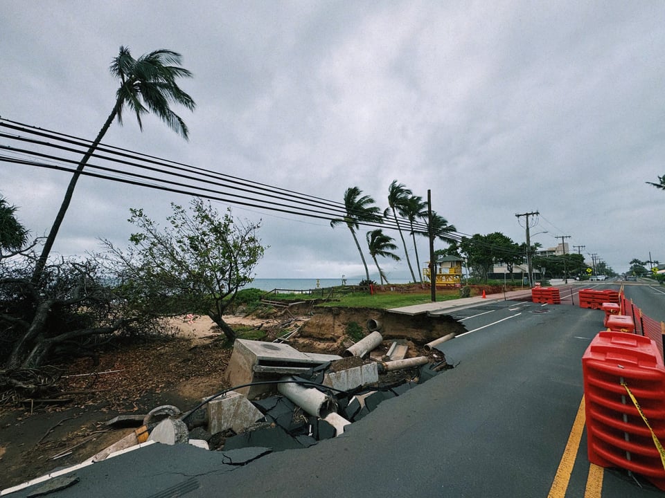 A sinkhole that has taken out a sidewalk and part of a main road