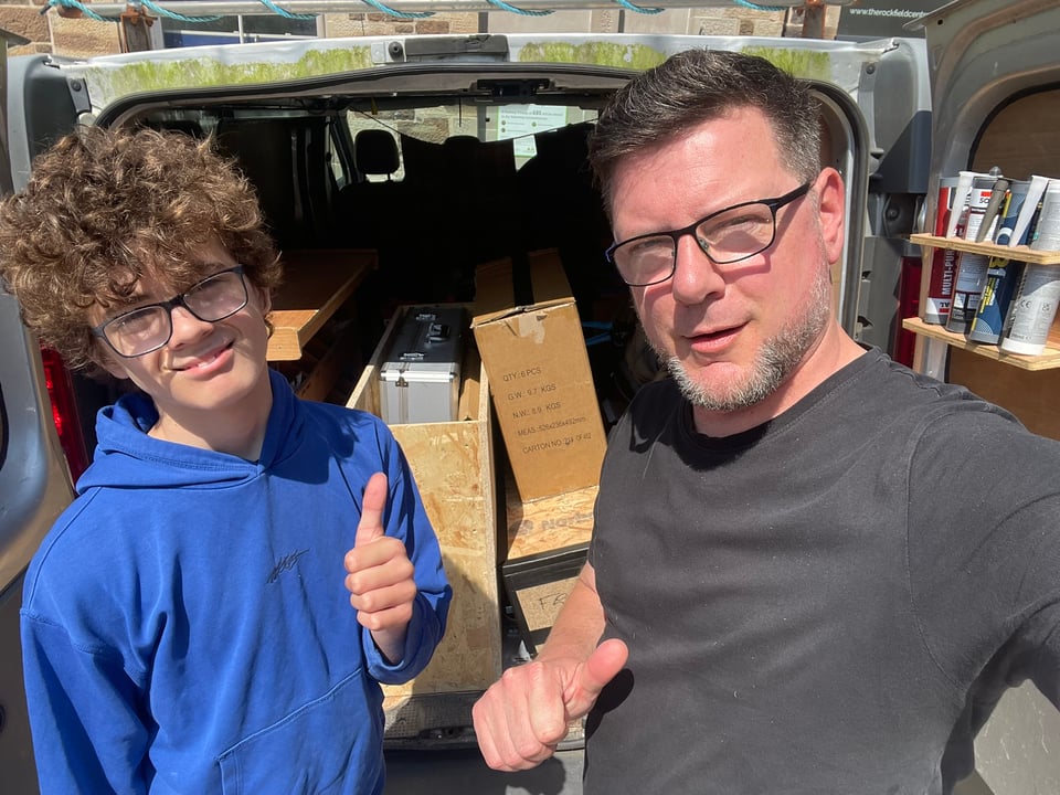Donald WG Lindsay and his son, standing in front of the rear door of a van, preparing to transport Dreaming Pipes' exhibition materials from Oban to Dundee.
