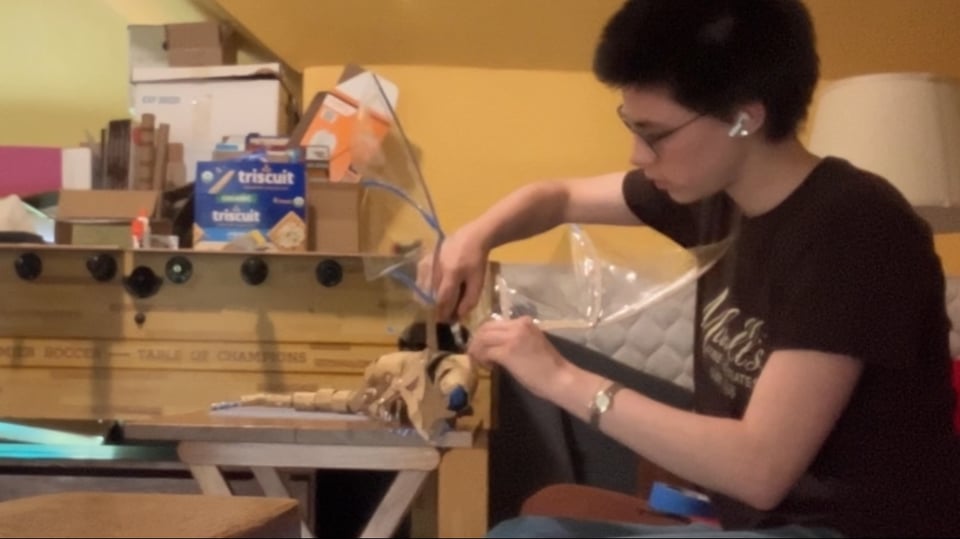 I stare intently at the dragon puppet as I hold a wing in place with one hand and pull wire into position with the other hand. The dragon puppet flops on the table in front of me.