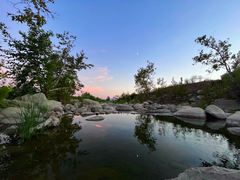A soothing photo of the Ventura River at dusk, the blue and pink sky reflected in the still water below.