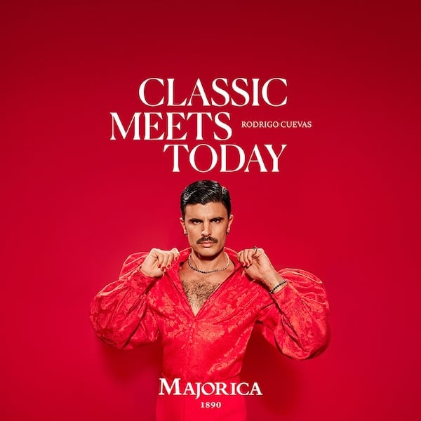 Imagen de Rodrigo Cuevas vestido de rojo sobre fondo rojo. Lleva bigote, perlas, uñas pintdas y una blusa de mangas anchas. Encima tiene el titular "Classic meets today", firmado por Majorica.
