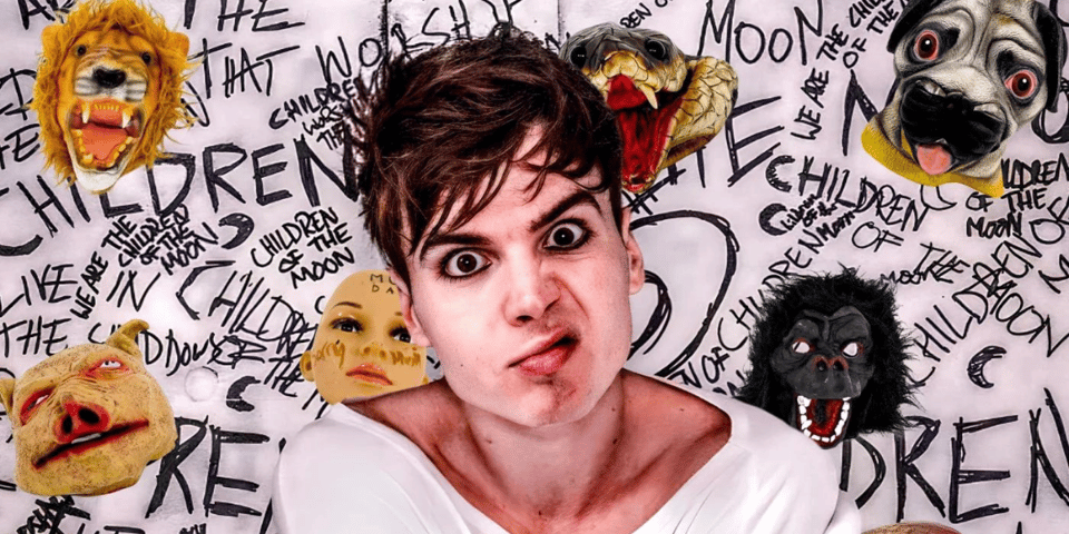 Ren in straitjacket against a backdrop of graffiti.