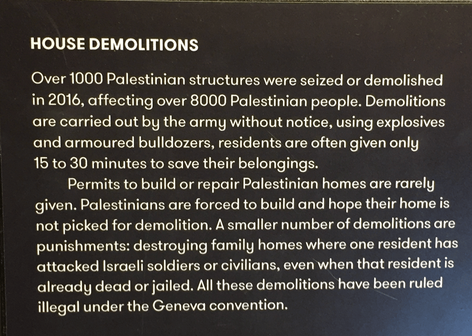 A photo of a sign in the museum that says: HOME DEMOLITIONS. Over 1000 Palestinian structures were seized or demolished in 2016, affecting 8000 Palestinian people. Demolitions are carried out by the army without notice, using explosives and armoured bulldozers, residents are often given only 15 to 30 minutes to save their belongings.
Permits to build or repair Palestinian homes are rarely given. Palestinians are forced to build and hope their home is not picked for demolition. A smaller number of demolitions are punishments: destroying family homes where one resident has attacked Israeli soldiers or civilians, even when that resident is already dead or jailed. All these demolitions have been ruled illegal under the Geneva convention.
