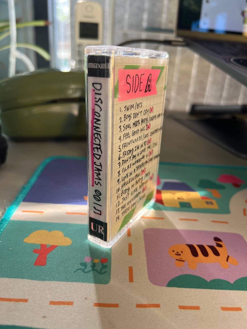 the cassette jewel case with a label in it that has all the tracks written on it standing upright on my desk next to my laptop