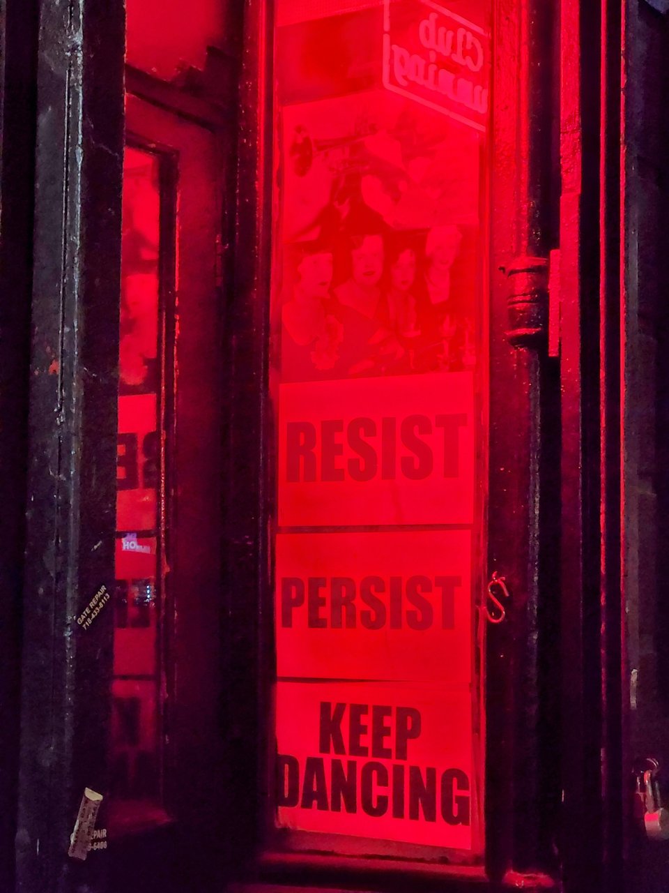 Photo of the doorway to Club Cumming, East Village, NYC, with a poster stating "resist, persist, keep dancing"