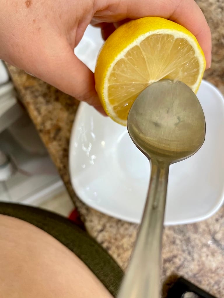 A lemon being squeezed by a spoon