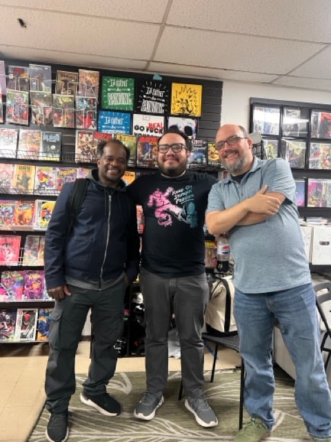 three men standing in front of a comic book store