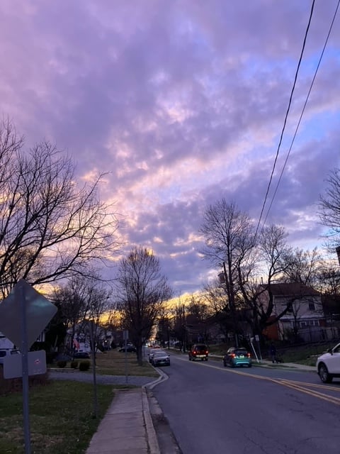 cars driving down a street at sunset