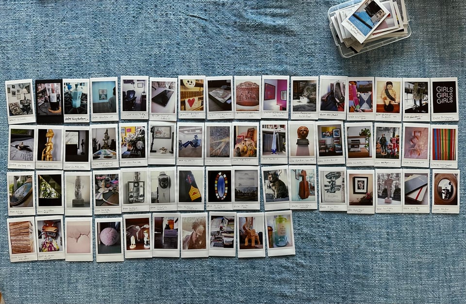 photo of 58 Instax prints spread out in 4 rows on a blue chambray tablecloth